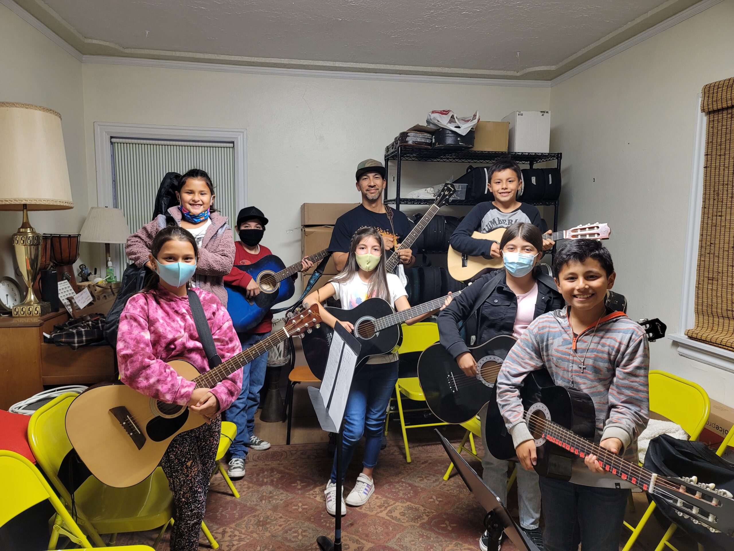 Children and their instructor holding guitars for their guitar class at Sol Treasures.